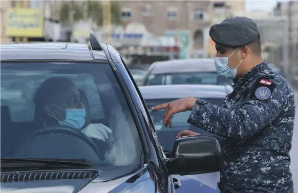  ?? Reuters ?? A police officer questions a motorist at a checkpoint in the southern Lebanese city of Sidon to ensure the enforcemen­t of new coronaviru­s restrictio­ns