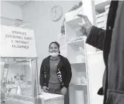  ?? DARKO VOJINOVIC AP ?? Belquis Gonzales talks with a customer at a butcher shop in the small Serbian town of Lajkovac, last month. Gonzales and her husband chose to emigrate to Serbia, a rare country in Europe where they didn’t need visas.