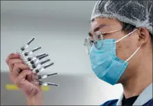  ?? NG HAN GUAN / AP ?? A laboratory technician inspects syringes of a COVID- 19 vaccine produced by Sinovac Biotech Ltd at its factory in Beijing on Sept 24.