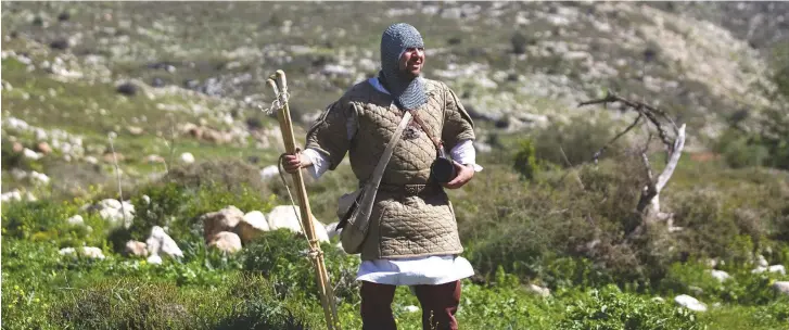  ?? (Reuters) ?? A MAN dressed up as a Crusader walks in a field during a lead up to a re-enactment of the battle of the Horns of Hattin.