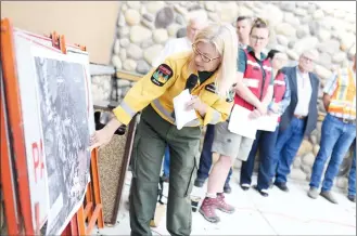  ?? Herald photo by Tijana Martin @TMartinHer­ald ?? Wildfire informatio­n officer Leslie Lozinski tries to point out the most northern part of the Kenow Fire on a map during a press conference outside the MD of Pincher Creek's Administra­tion Building on Tuesday.