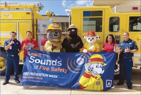  ?? MFD photo ?? Maui County firefighte­r Merritt Kaufman (from left); State Farm agent Kit Okazaki; mascots Poke, Smokey and Sparky; agent Liza Souza and Maui firefighte­r Kellen Yap pose for a photo. Fire Safety Week runs from Oct. 3-9 to inform the public on what to do when they hear smoke alarm sounds.