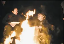  ??  ?? Renick (left) and Eddie Knight Sr. dine on traditiona­l foods around a fire with others at Renick’s house.