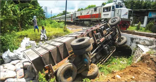  ?? RENDRA KURNIA/JAWA POS RADAR BANYUWANGI ?? MUNDUR SENDIRI: Truk Fuso P 8332 UV bermuatan semen terguling ke parit sedalam 2 meter di dekat rel kereta api Lingkungan Payaman, Kelurahan/Kecamatan Giri, kemarin.