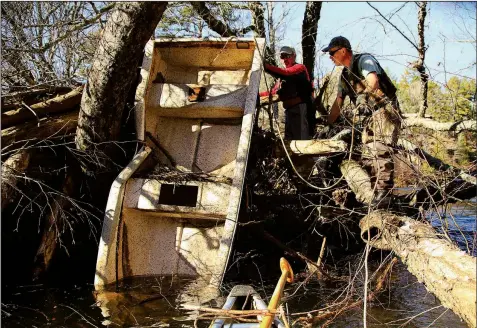  ??  ?? Roger Head (left) and Cowper Chadbourn work at dislodging a trashed boat from its nest in downed trees on Cadron Creek.