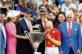  ?? GETTY IMAGES ?? Victory — and the Triple Crown trophy — taste even sweeter for jockey Mike Smith and trainer Bob Baffert (far right) after Justify’s victory in the Belmont Stakes.