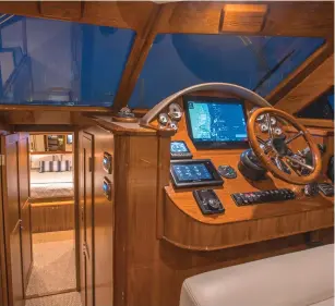  ??  ?? top and above: The owner opted for a high-gloss teak throughout the salon and helm, with a matte finish below in the staterooms. Note the large windows, which allow panoramic views, with power windows to port and starboard by the helm, and on the aft bulkhead. You can watch TV while sitting under the stars on the aft bench seat.