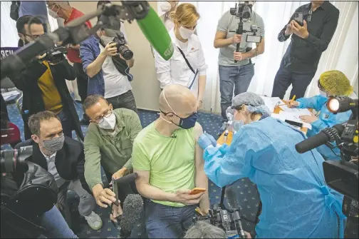  ?? (AP/Pavel Golovkin) ?? German tourist Uwe Keim (center) gets his first shot of Russia’s Sputnik V coronaviru­s vaccine in Moscow.