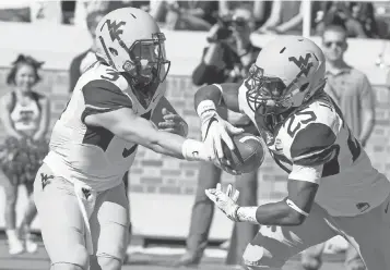  ?? MICHAEL C. JOHNSON, USA TODAY SPORTS ?? “This is a team that doesn’t quit fighting,” says West Virginia quarterbac­k Skyler Howard, left, handing the ball off to running back Justin Crawford on Saturday vs. Texas Tech.