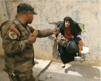  ?? PHOTO AFP ?? Un soldat accueille une femme qui fuit la vieille ville de Mossoul contrôlée par L’ÉI.