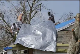  ?? DAVID J. PHILLIP — THE ASSOCIATED PRESS ?? Gary Johnston, left, Grant Boughamer, center, and Jose Garcia, right, on Thursday place a tarp on a roof in Golden Meadow, La., damaged by Hurricane Ida.