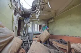  ?? AFP VIA GETTY IMAGES ?? A woman clears rubble in her daughter’s damaged apartment, which was hit by recent shelling in what local officials called a Ukrainian military strike in Donetsk, Russian-controlled Ukraine, on Thursday.