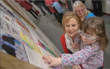  ?? ERIC BONZAR — THE MORNING JOURNAL ?? While in the arms of Victim Services Director Kathy Rednour-Esser, 5-year-old Jasmine Hoholski places her fingers on a memorial tile she created in remembranc­e of her mother Catherine “Kat” Hoholski. On April 3, the Lorain County Prosecutor’s Office...