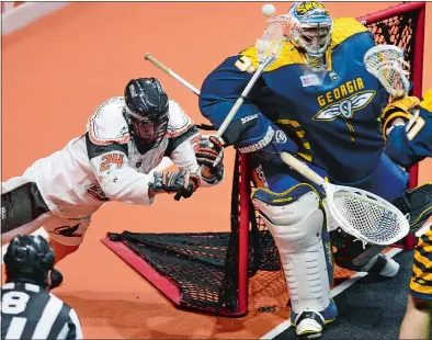  ?? SARAH GORDON/THE DAY ?? New England’s Joel Coyle (24) reaches around and attempts a shot on Georgia Swarm goalie Mike Poulin during Friday night’s season-opener at Mohegan Sun Arena where the Black Wolves beat the Swarm 13-11.