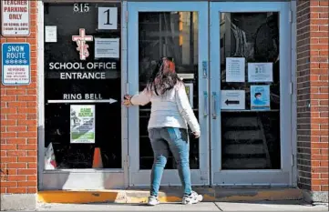  ?? STACEY WESCOTT/CHICAGO TRIBUNE ?? A woman enters Sacred Heart School on Friday in Melrose Park. The Archdioces­e of Chicago will close the school.