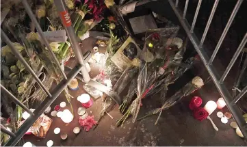  ??  ?? Photo shows lightened candles, flowers and a paper reading a message which can be translated as ‘and to those who remain, keep going’ at a makeshift memorial outside the Bataclan concert hall in tribute of the victims of the attack. — AFP photo