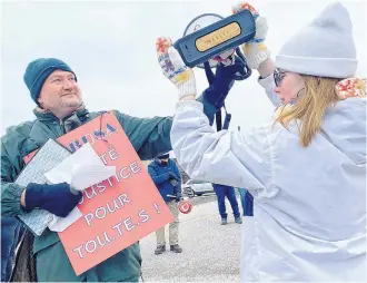  ?? TINA COMEAU ?? Striking Université Sainte-Anne professor Darryl Whetter holds a megaphone up to a speaker on March 9 as the Twisted Sister song ‘We’re Not Gonna Take It’ was played outside of the Francophon­e/Acadian university in Church Point, Digby County.