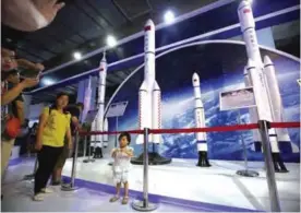  ??  ?? BEIJING: In this photo, a girl stands in front of models of Chinese space rockets, including the Long March 5, second from left, at the China Beijing Internatio­nal High-Tech Expo in Beijing. —AP