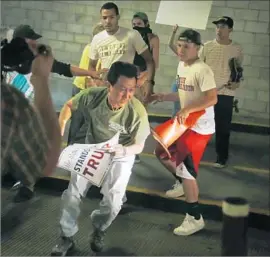  ?? Patrick Tehan ?? PROTESTERS HARASS a Trump supporter in the convention center parking garage. Some “Make America great again” ball caps were stolen and set on fire.