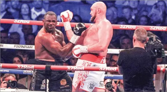  ?? AFP ?? Britain’s Tyson Fury (right) lands an uppercut to knock out Britain’s Dillian Whyte in the sixth round and win the WBC heavyweigh­t title fight at Wembley Stadium in west London.