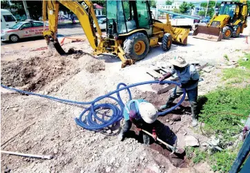  ?? GLADSTONE TAYLOR/MULTIMEDIA PHOTO EDITOR ?? National Water Commission employees Bobby Lewin (left) and Delroy Cherringto­n hard at work reconnecti­ng the water supply to Tile City on Constant Spring Road, St Andrew, on Friday. Tile City has been experienci­ng water disruption due to the road developmen­t along Constant Spring Road over the past few months.