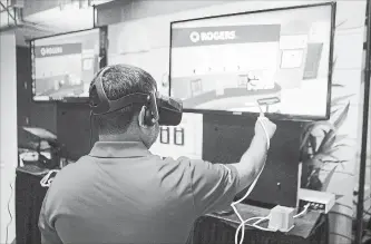  ?? CHRIS YOUNG THE CANADIAN PRESS ?? A Rogers employee wears VR goggles as he stands at a stall promoting VR retail over 5G, at a press event in Toronto on Monday.