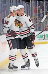  ?? GETTY IMAGES ?? Jonathan Toews (left) celebrates with Connor Murphy after scoring the winning goal in overtime Thursday against the Bruins.