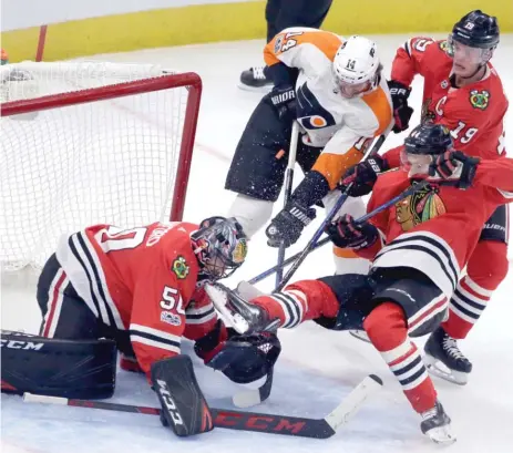  ??  ?? Flyers center Sean Couturier tries to stuff the puck past Corey Crawford during the second period Wednesday at the United Center. | NAM Y. HUH/ AP