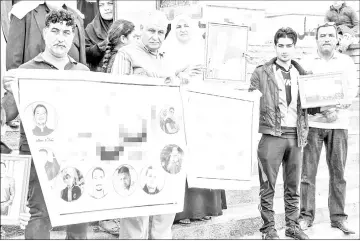  ??  ?? Iraqis hold up posters and portraits of missing relatives.