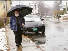  ?? Associated Press ?? A Brattlebor­o, Vt., resident carries an umbrella while walking down Elliot Street as the snow switches to rain on Wednesday, Nov. 16.