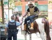  ?? ASHLEE REZIN GARCIA/SUN-TIMES ?? Adam Hollingswo­rth, aka the Dread Head Cowboy, shakes hands with a CPD officer as he rides his horse in the Loop in June.