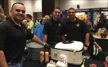  ?? KEVIN MARTIN — THE MORNING JOURNAL ?? Troopers Ray Santiago , left, Corey Resendez and Sgt. Pablo Cruz of the Ohio State Highway Patrol Elyria Post serve up their winning liquid concoction “Thin Blue Line Shine” at the 17th annual Zero-Proof Mix-Off at Lorain County Community College’s Spitzer Conference Center on Dec. 6.