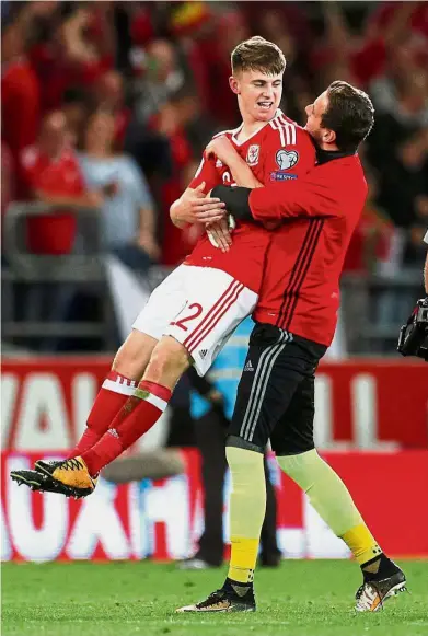  ??  ?? Well done, son!: Wales’ goalkeeper Danny Ward celebrates by lifting Ben Woodburn during the World Cup qualifying Group D match against Austria in Cardiff on Saturday. Wales won 1- 0. — Reuters