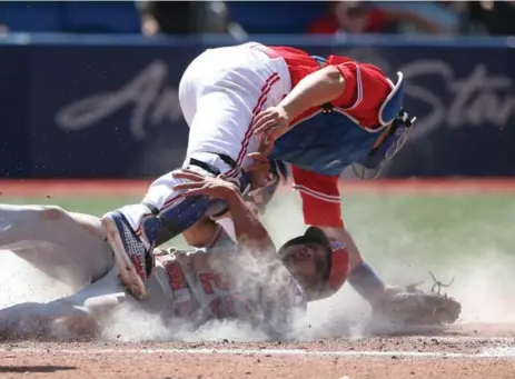  ?? TOM SZCZERBOWS­KI/GETTY IMAGES ?? Angels baserunner Ben Revere beats the tag from Jays catcher Miguel Montero, but pays a price, in the fifth inning of Sunday’s game.