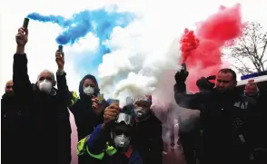  ?? (Gonzalo Fuentes/Reuters) ?? FRENCH AMBULANCE drivers hold blue, white, red smoke bombs yesterday during a demonstrat­ion at the Place de la Concorde in Paris.