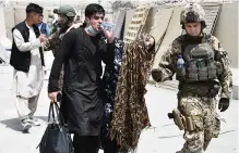  ??  ?? Helping hand... soldiers aid a woman after she falls while fleeing Kabul