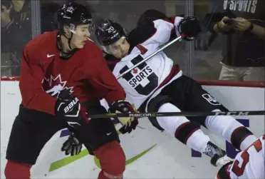  ?? NATHAN DENETTE, THE CANADIAN PRESS ?? Canada’s Logan Stanley, left, hits U Sports’ Brett Welychka during first-period exhibition hockey action in St. Catharines on Thursday.