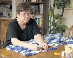  ??  ?? Connie Bauldridge finger-knits a baby blanket. “We have a family with a lot of health problems, plus I’m not a spring chicken,” the 70-year-old former nurse said of the decision to forgo a large annual Thanksgivi­ng dinner this year.