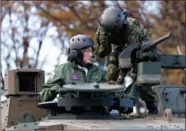  ?? (File Photo/AP/Pool/Kiyoshi Ota) ?? Kishida (left) rides Nov. 27 on a Japan Ground Self-Defense Force Type 10 tank during a review at the JGSDF Camp Asaka in Tokyo.