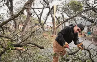  ?? Jay Janner/Associated Press ?? Jojo Mairena-Davila removes a tree from his yard in Austin, where dense tree canopy was blamed for widespread downed power lines. Power has been out for many in the city for three days.