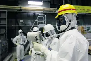  ?? KIMIMASA MAYAMA/ EPA FILES ?? An official checks radiation at the Fukushima plant. Scientist Ken Buesseler believes there is a lot of fear over radiation because people can’t touch, smell or feel it, yet they know it causes cancer.