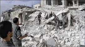  ?? SYRIAN CIVIL DEFENSE WHITE HELMETS VIA AP ?? Civil-defense workers and civilians inspect a damaged building after a rare U.S. strike hit a rebel-held suburb near Damascus, Syria, on Thursday. Dozens were reported killed in the strike on Syria’s government-backed troops.