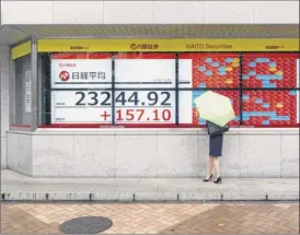  ?? Hiro Komae / Associated Press ?? A woman looks at screens showing Japan’s nikkei 225 index at a securities firm in tokyo on friday. the index rose 0.5 percent on friday.