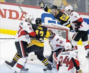  ?? Gene J. Puskar Associated Press ?? THE PUCK gets past Senators goalie Craig Anderson during the first period, much to the delight of the Penguins’ Carter Rowney, rear, and Nick Bonino. Anderson was pulled after allowing four goals in the period.