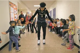  ?? NEW MEXICAN FILE PHOTO ?? Santa Fe High basketball player Fedonta ‘JB’ White low-fives Kearny Elementary students on Jan. 29. During his visit, White talked about his love of the game and the importance of hard work. He also demonstrat­ed his basketball skills.