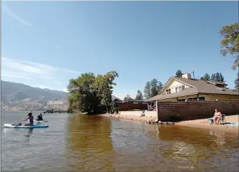  ?? Herald ?? JOE FRIES/Penticton
Paddleboar­ders go for a spin Friday on Skaha Lake where the public beach turns into private property that is currently designated for future park use, although city council will be asked next week to reconsider that.