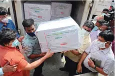  ?? — AFP ?? Health workers carry a box of Covishield vaccine to a cold storage unit from a vehicle at the Regional Vaccine Storage centre in Chennai.