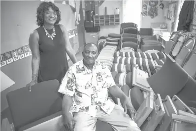  ??  ?? Assata Thomas, left, poses for a photograph on July 27 with her father George Gregory, pastor and founder at First Fellowship Baptist Church, among some of the new pews that will replace the 45-yearold pews in the church sanctuary in Dallas. The old pews were made of particle board that were destroyed by water when a pipe broke in January.