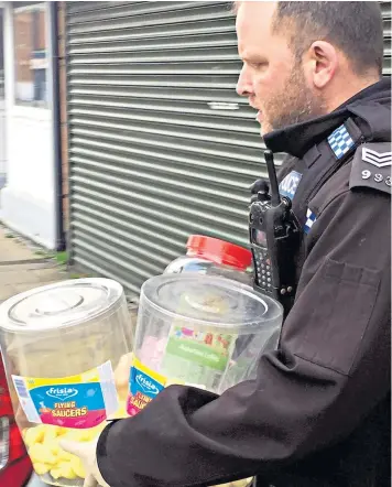  ??  ?? Police remove jars and boxes from a sweet shop in County Durham amid fears it could be contaminat­ed by dangerous drugs, loading the entire stock into a car