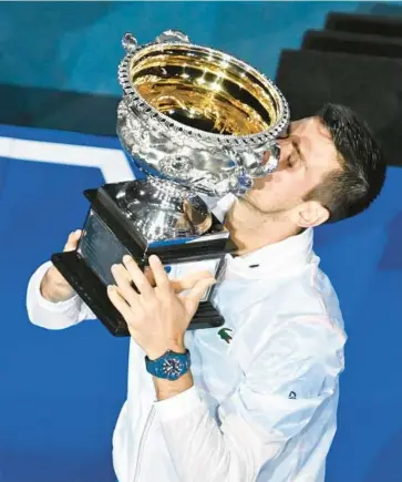  ?? PAUL CROCK/GETTY-AFP ?? Novak Djokovic kisses the Australian Open trophy after winning his 22nd career Grand Slam title Sunday.